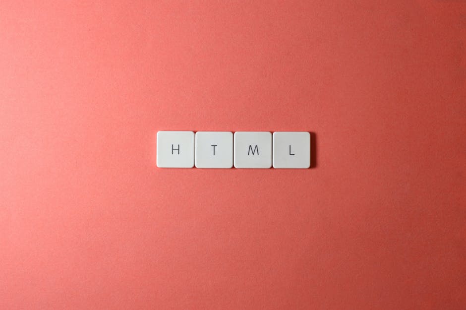 A close-up of four white keyboard keycaps arranged in a row on a smooth, pink-colored surface. Each keycap displays a black letter, spelling out 'HTML'. The surface appears clean and matte, with soft 